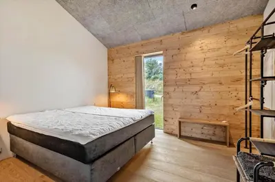 a bedroom with a bed and a wooden wall at LK2174-Lokken-Stellavej-18 in Løkken