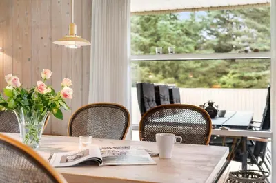 a table with a vase of flowers and a book at LK2178-Lokken-Sarasvej-48 in Løkken