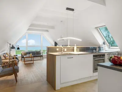 a kitchen with white cabinets and a living room at Holiday Home Raika - 25m to the fjord by Interhome in Vestervig
