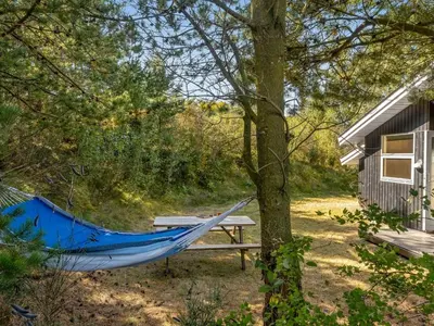 a hammock and a picnic table in front of a cabin at Holiday Home Marisol - 250m to the fjord by Interhome in Fur
