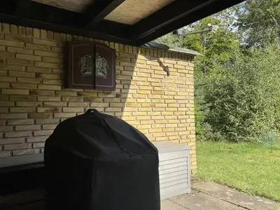 a building with a black cover next to a brick wall at Holiday Home Karmen - 1km from the sea by Interhome in Pandrup