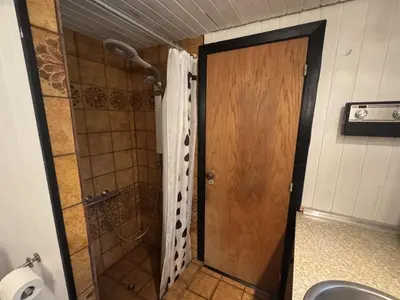a bathroom with a shower and a wooden door at Holiday Home Karmen - 1km from the sea by Interhome in Pandrup