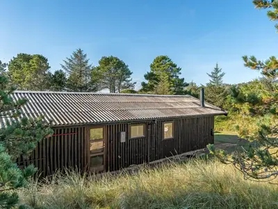 a cabin in the woods with a metal roof at Holiday Home Anneka - 750m from the sea by Interhome in Pandrup