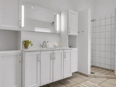a white kitchen with a sink and a shower at Holiday Home Alde - 150m from the sea by Interhome in Blokhus