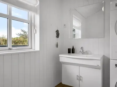 a white bathroom with a sink and a window at Holiday Home Alde - 150m from the sea by Interhome in Blokhus