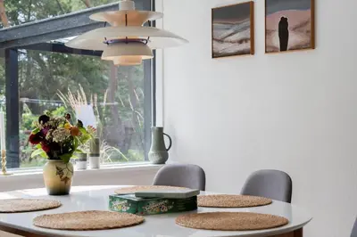 a dining room table with chairs and a vase of flowers at 1357-Snedsted-Grahavrevej-1 in Snedsted