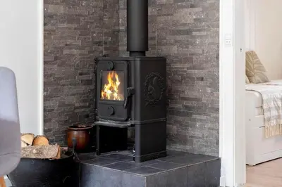 a wood stove in a room with a brick wall at 1357-Snedsted-Grahavrevej-1 in Snedsted