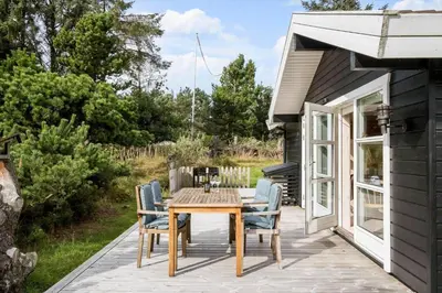 a patio with a wooden table and chairs at BL1121-Saltum-Daadyrvej-7 in Saltum