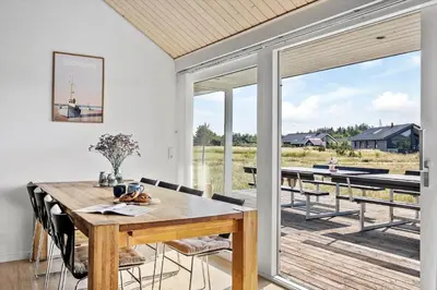 a dining room with a wooden table and a large window at JB367-Brovst-Kronvildtvej-102 in Brovst