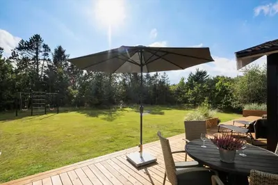 a table with an umbrella on a wooden deck at BL1123-Saltum-Jydske-Rev-5 in Saltum