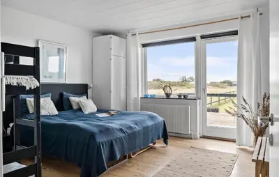 a bedroom with a blue bed and a large window at Awesome Home In Harboøre With Sauna in Harboør