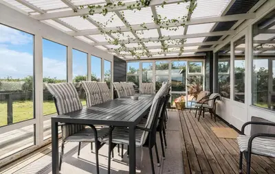 a screened porch with a wooden table and chairs at Awesome Home In Harboøre With Sauna in Harboør