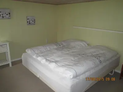 a white bed in a room with green walls at Bakkegården Homestay in Spottrup