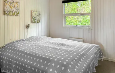 a bedroom with a bed with a black and white comforter at Awesome Home In Farsø With Sauna in Farsø