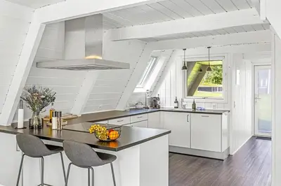 a kitchen with white cabinets and a table and chairs at Holiday Home At Himmerland Golf & Spa Resort in Farsø