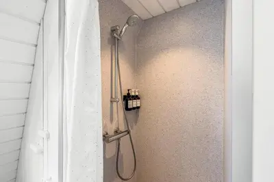 a shower with a shower head in a bathroom at Holiday Home At Himmerland Golf & Spa Resort in Farsø