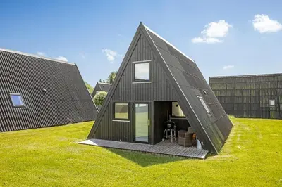 a black clad house in a field of grass at Holiday Home At Himmerland Golf & Spa Resort in Farsø