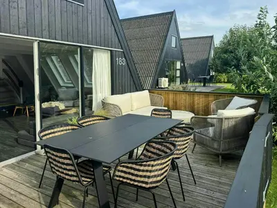 a black table and chairs on a wooden deck at Holiday Home At Himmerland Golf & Spa Resort in Farsø