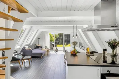 a kitchen and living room with a couch and a table at Holiday Home At Himmerland Golf & Spa Resort in Farsø