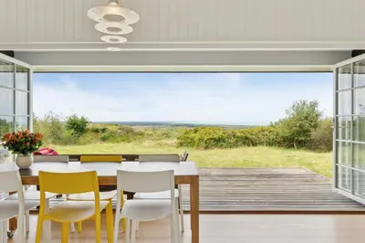 a dining room with a table and chairs and a large window at Family House With Sea View In Svinkløv in Fjerritslev