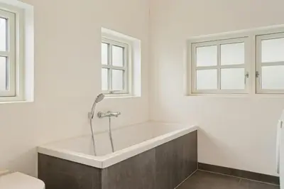 a bath tub in a bathroom with two windows at Family House With Sea View In Svinkløv in Fjerritslev