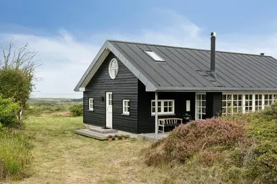 a black house sitting on top of a field at Family House With Sea View In Svinkløv in Fjerritslev