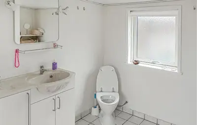 a bathroom with a toilet and a sink and a window at Lovely Home In Thyborøn With Wifi in Thyborøn