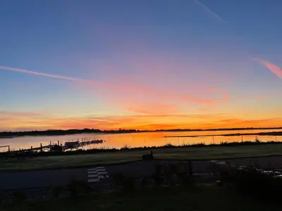 a sunset over a body of water with a dock at Udsigtsvilla Tambohus in Thyholm