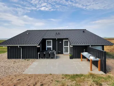 a black house with a table and chairs in front of it at Holiday Home Arisa - 100m to the fjord by Interhome in Løgstør