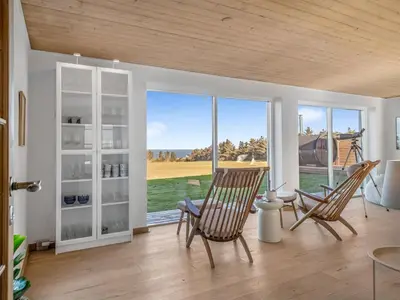 a living room with two chairs and a large window at Holiday Home Elida - 400m from the sea by Interhome in Hanstholm
