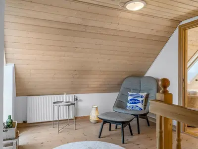 a chair and stool in a room with a wooden ceiling at Holiday Home Elida - 400m from the sea by Interhome in Hanstholm