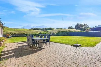 a patio with a table and chairs and a lawn at 3007Møllehuset - Stuehus in Blokhus