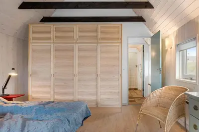 a bedroom with a large wooden closet and a bed at BL1120-Saltum-Kohlsvej-15 in Saltum