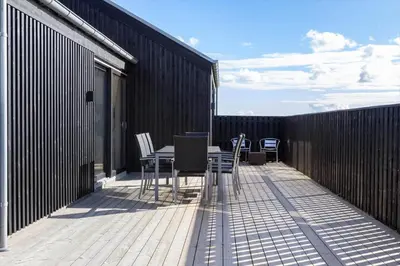 a balcony with a table and chairs on a fence at LK2159-Lokken-Kringelbaekvej-27 in Løkken