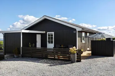 a black house with a fence and an umbrella at LF14058-Roslev-Eskovvej-58 in Roslev