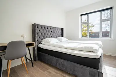 a bedroom with a bed and a desk and a window at Holstebro Apartments in Holstebro