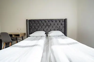 two beds in a bedroom with a black headboard at Holstebro Apartments in Holstebro
