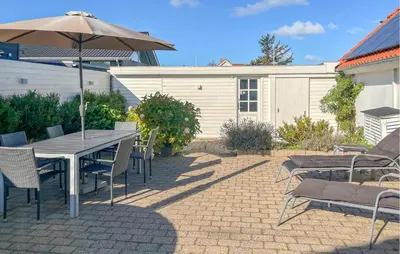 a patio with a table and chairs and an umbrella at 3 Bedroom Nice Home In Blokhus in Blokhus