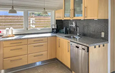 a kitchen with wooden cabinets and a stainless steel dishwasher at 3 Bedroom Nice Home In Blokhus in Blokhus