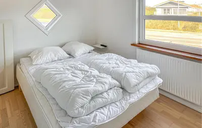 a white bed in a room with a window at 3 Bedroom Nice Home In Blokhus in Blokhus