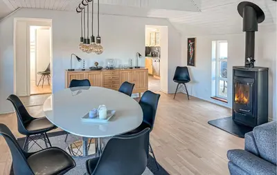 a living room with a table and chairs and a stove at 3 Bedroom Nice Home In Blokhus in Blokhus