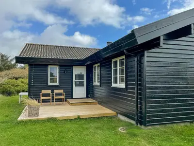 a black tiny house with a wooden deck at Authentic Wooden House By The North Sea in Vestervig