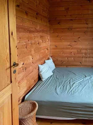 a small bed in a wooden cabin with a door at Authentic Wooden House By The North Sea in Vestervig