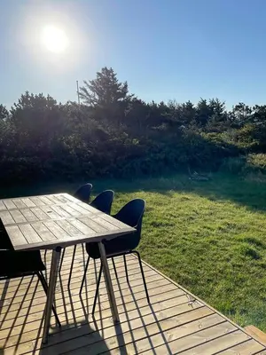 a wooden deck with a table and chairs and a field at Authentic Wooden House By The North Sea in Vestervig