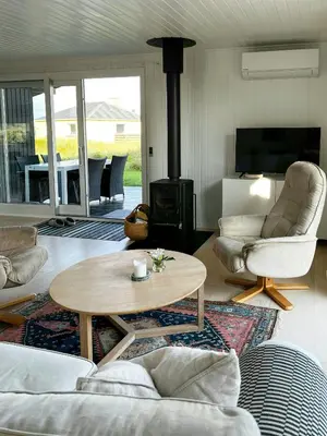 a living room with a table and a wood stove at Family House Close To The Sea At Tranum Strand in Brovst