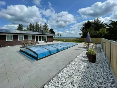 a backyard with a swimming pool and a house at Holiday Home With Pool And Fjord Views On Lundø in Højslev