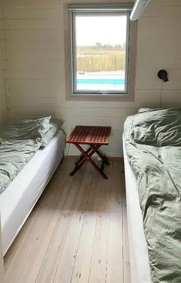 a room with two beds and a table next to a window at Holiday Home With Pool And Fjord Views On Lundø in Højslev