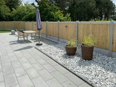 a patio with a table and an umbrella and plants at Holiday Home With Pool And Fjord Views On Lundø in Højslev