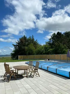 a table and two chairs next to a swimming pool at Holiday Home With Pool And Fjord Views On Lundø in Højslev