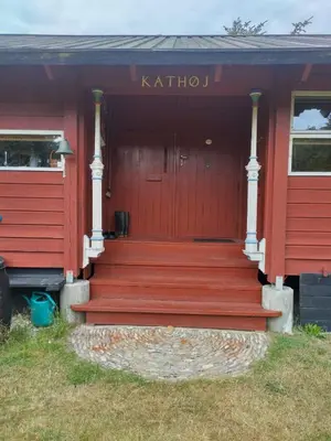 a red house with a red door and stairs at Kathøje in Lemvig